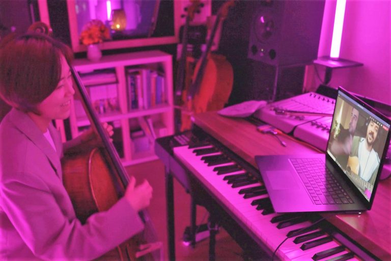 mulher com violão celo no braço e teclado na frente