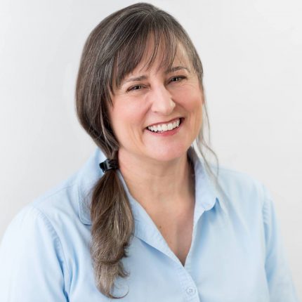 mulher de cabelo preso sorrindo para foto