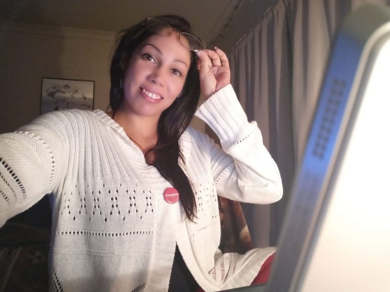 mulher levantando o óculo, sentada perto de monitor