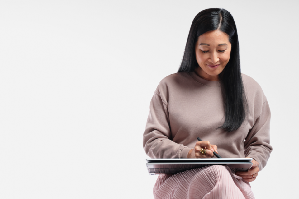 mulher sentada com note no colo sorrindo