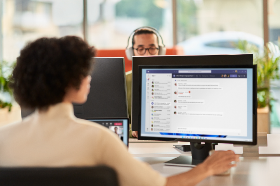 Mulher de costas trabalha em frente a um computador com o Microsoft Teams aberto