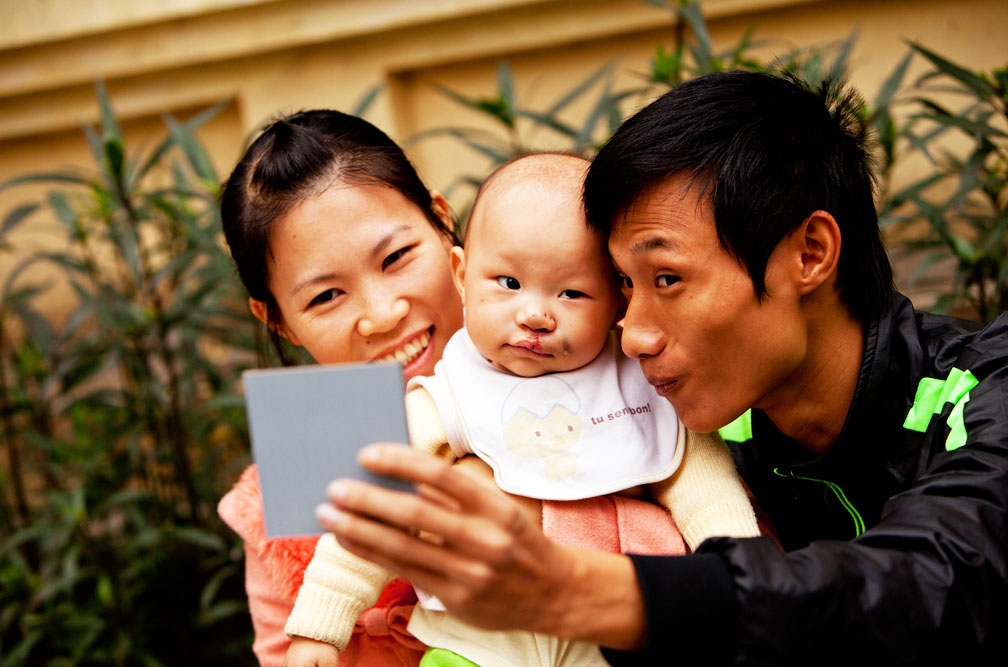 Post-operation, it’s all smiles as a child and her parents look in a mirror at the Operation Smile Hanoi mission site.
