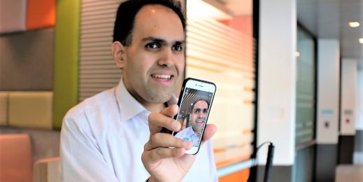 Saquib Shaihk holds up his smartphone with the Seeing Ai app activated.