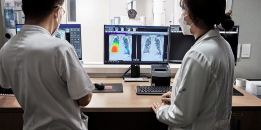 Two people look at X-ray images on a computer screen