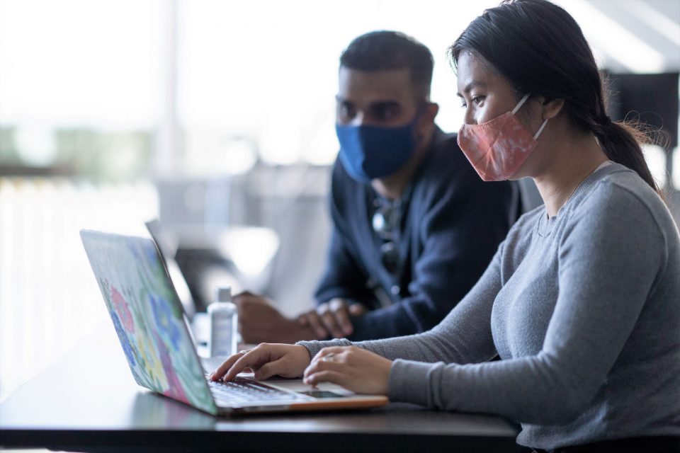 masked colleagues working on laptop