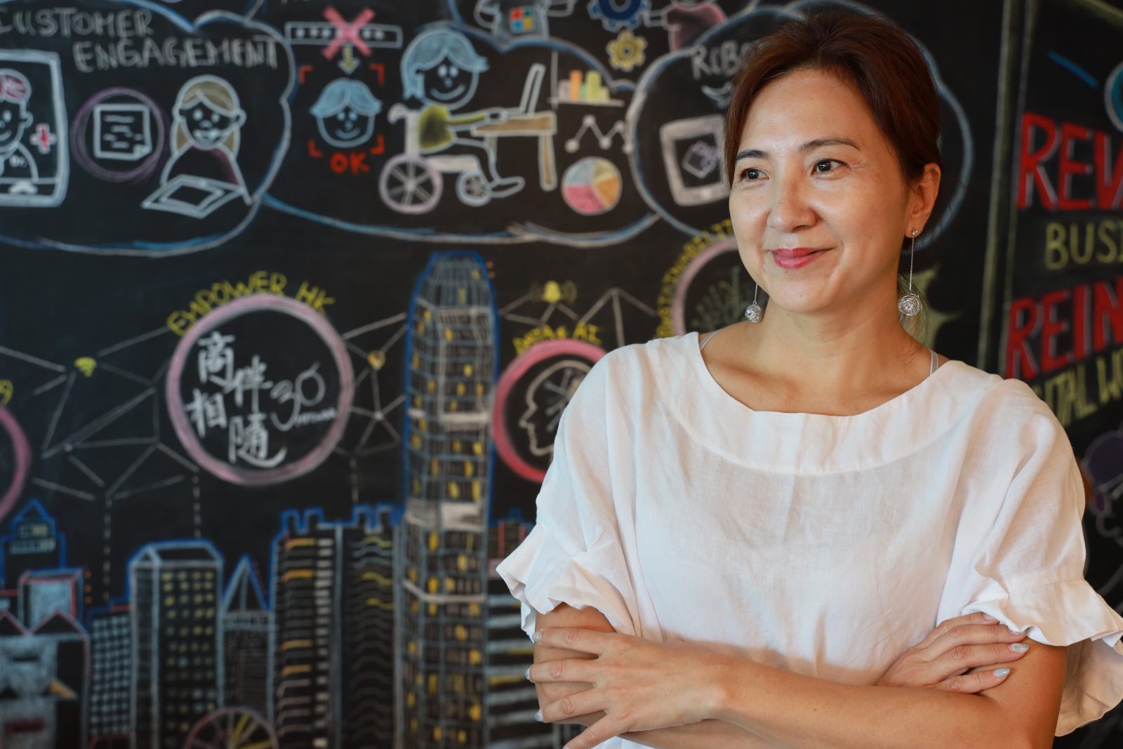 A smiling woman in front of a chalkboard