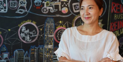 A smiling woman in front of a chalkboard