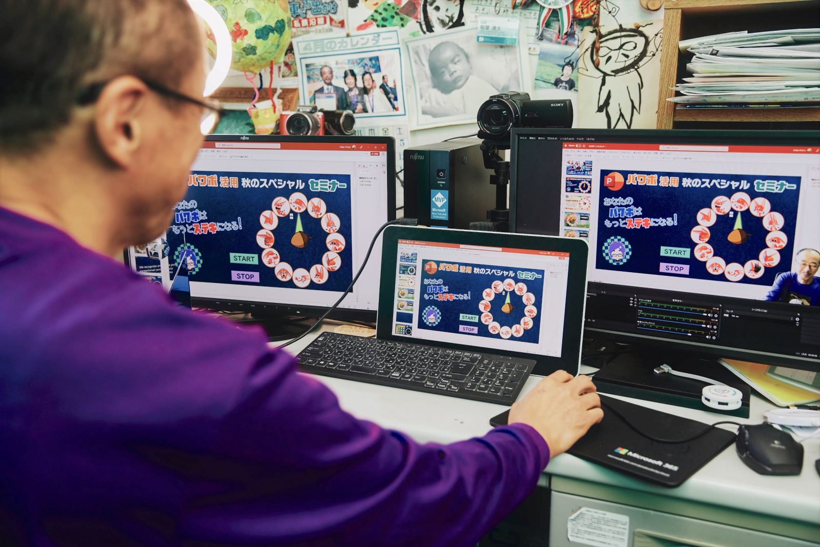 A man sits in front of several computer screens.