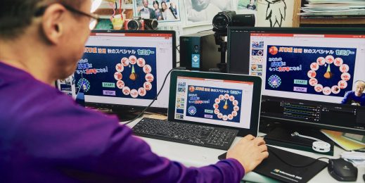 A man sits in front of several computer screens.