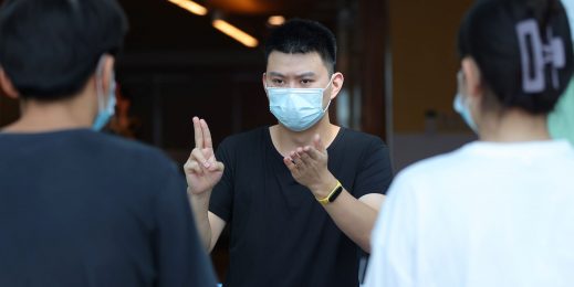 A man in a mask converses in sign language