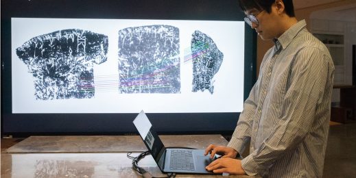 Researcher using a laptop to study the Oracle Bones. Large screen displays what he is viewing on the laptop.