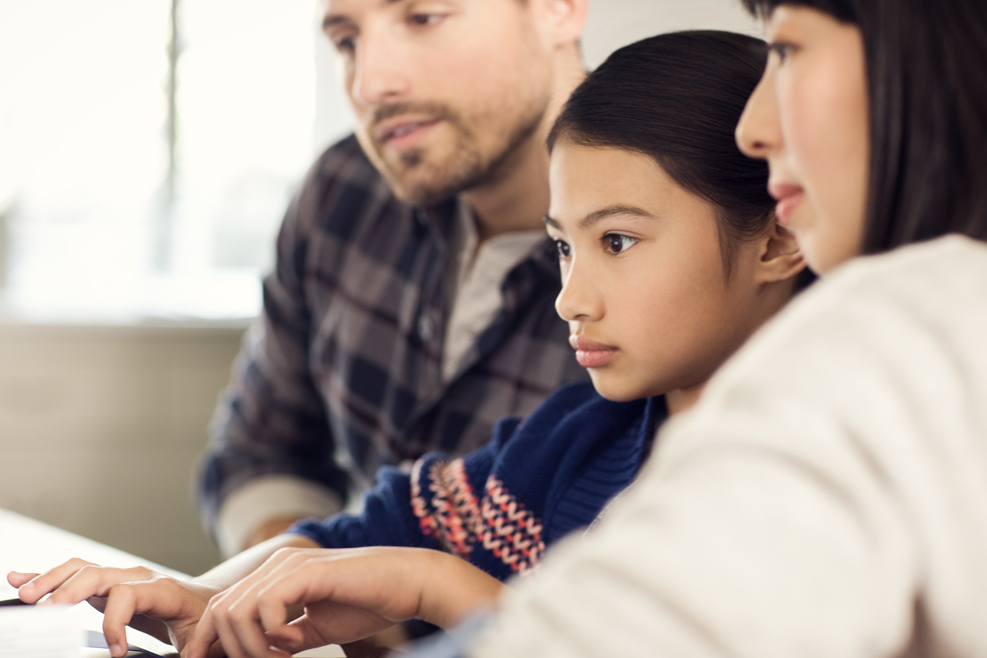 Male, female and child working together on laptop in family room. Homework, studying.