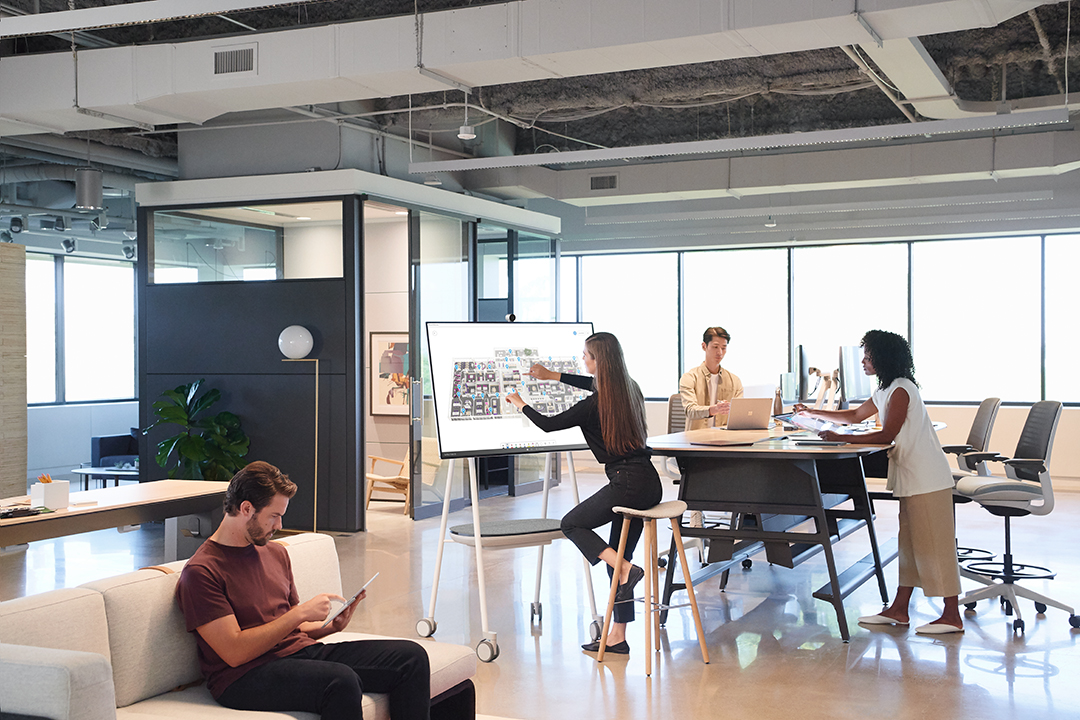 Kuvassa on joukko ihmisiä työskentelemässä Surface Hub 2S:n ympärillä.