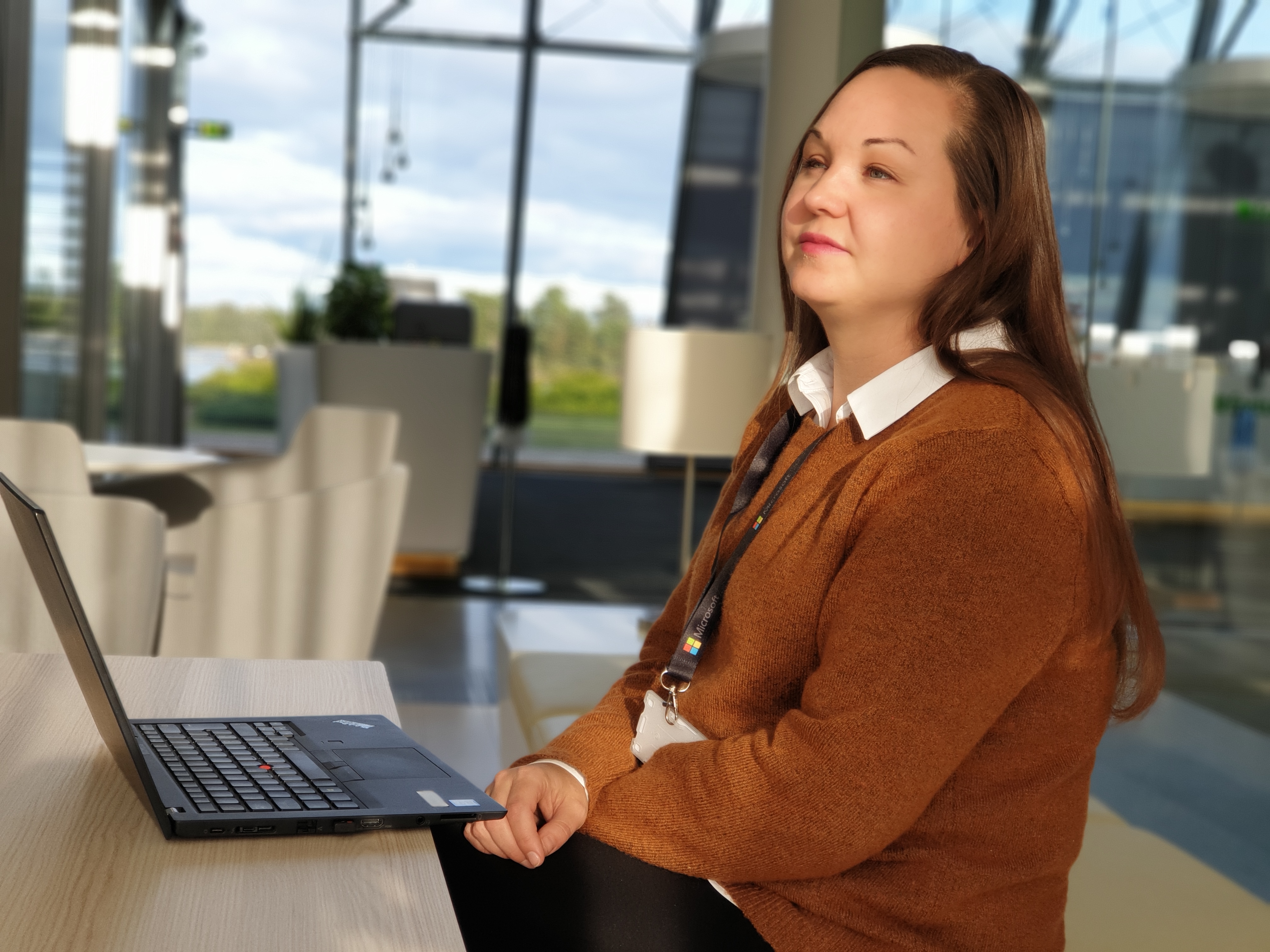 Kuvassa on Tekoälytaitaja Elina Rajuvaara pöydän ääressä kannettavan tietokoneensa kanssa