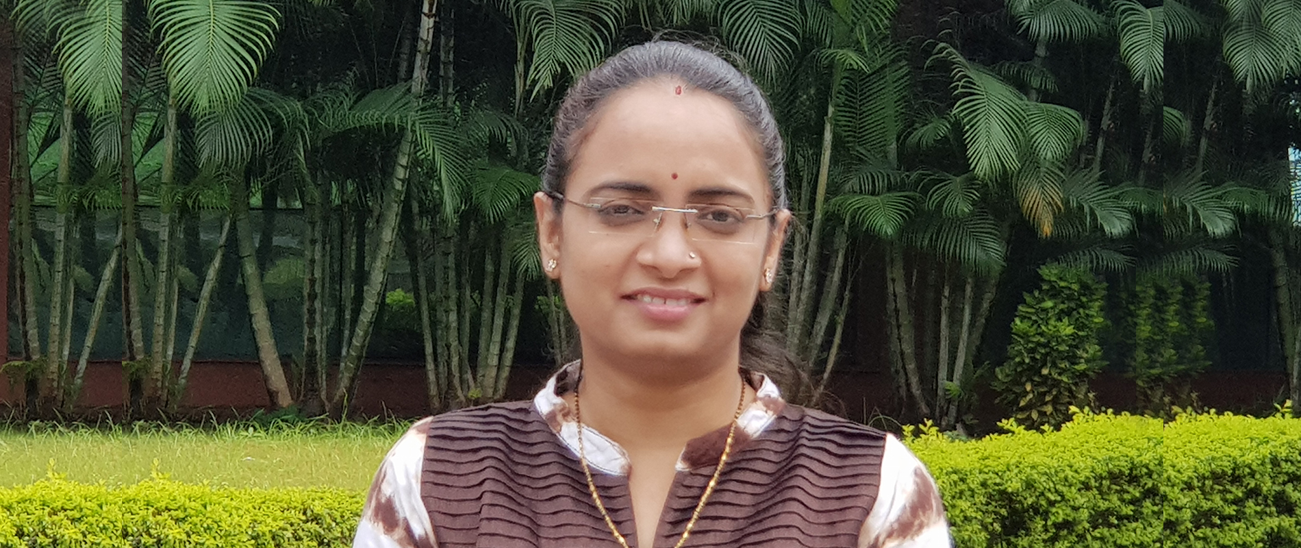 A woman standing with trees in the background