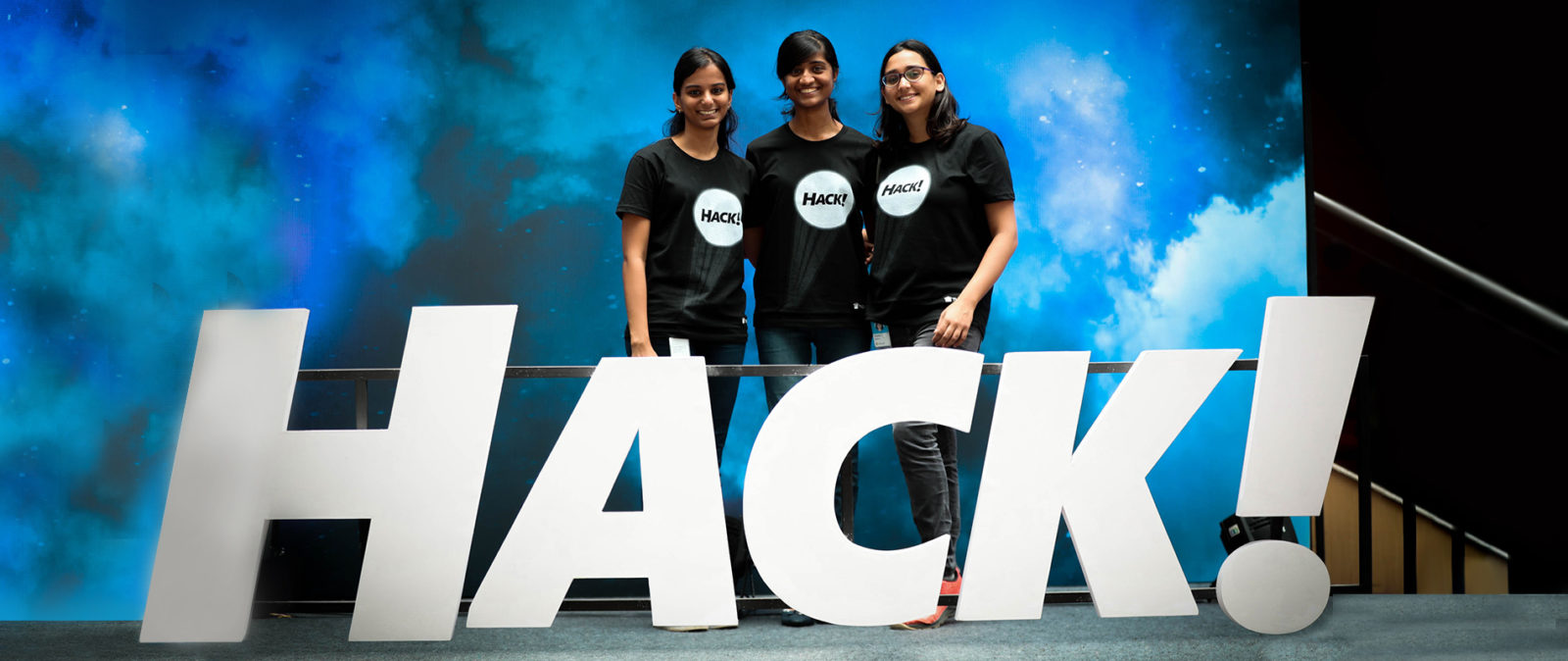 Three women smiling at the camera during a corporate event
