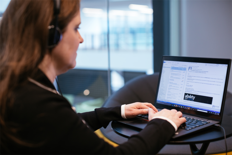 A woman working on a laptop using microsoft ease of accessiblity