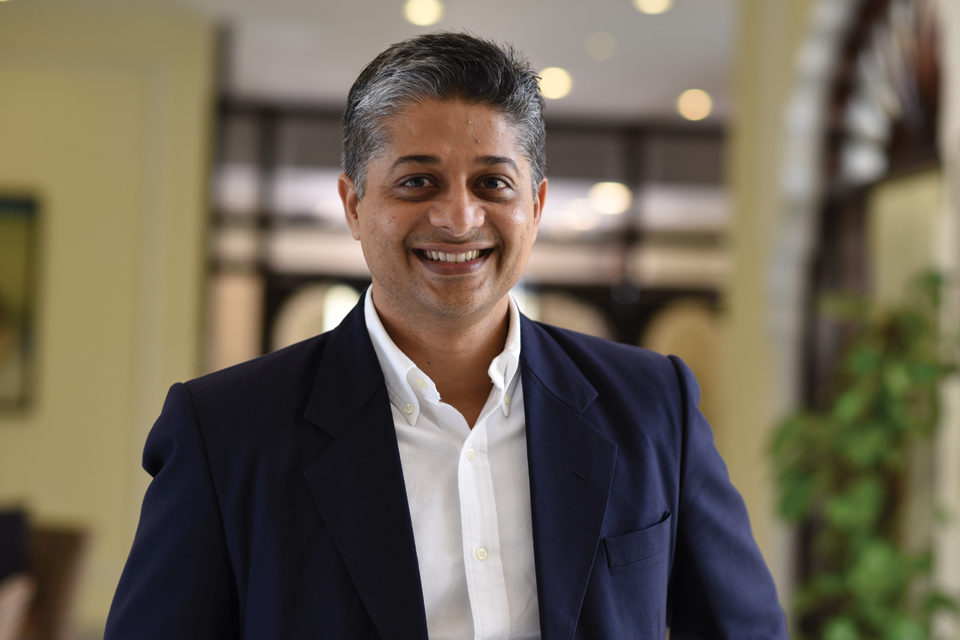 A man wearing a blazer, smiling at the camera