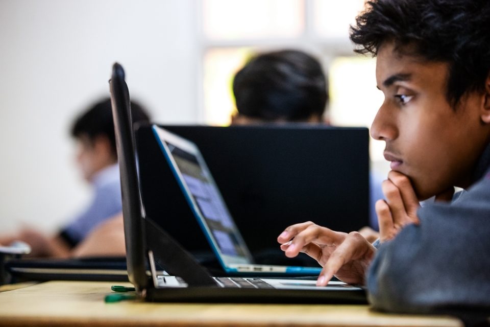 Photo of a boy looking at a laptop in a classroom