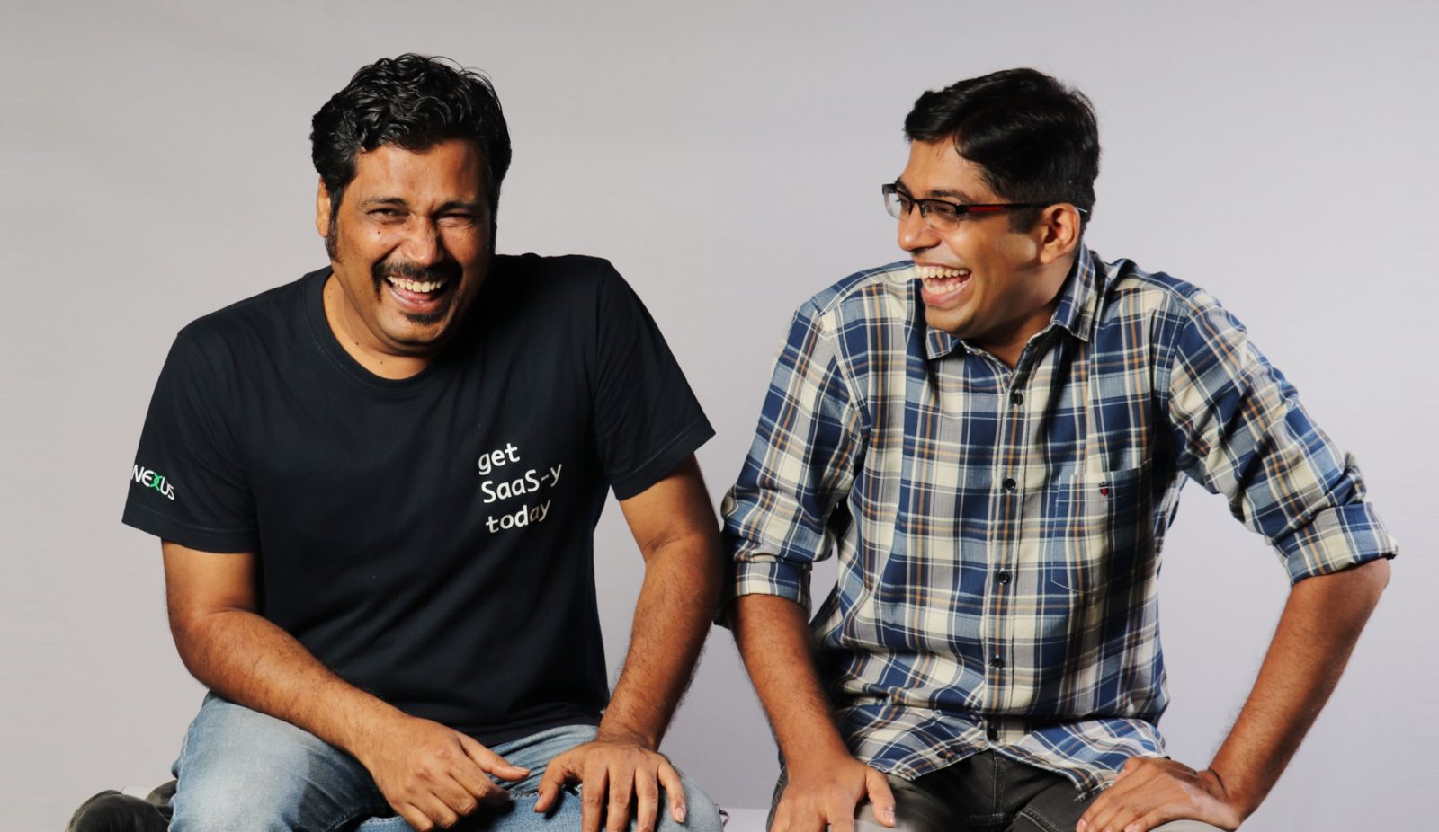 Photo of two men sitting on a bench and laughing