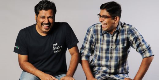 Photo of two men sitting on a bench and laughing