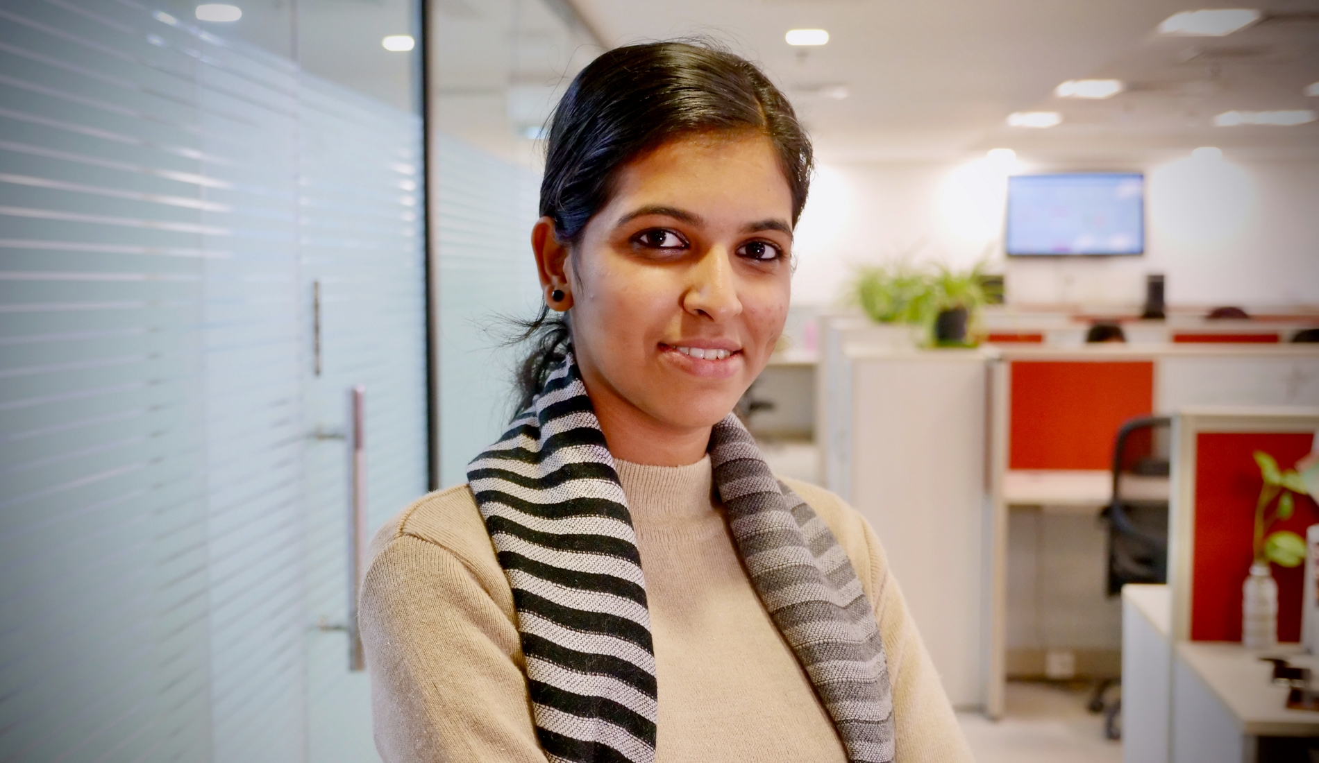 Photo of a young woman in an office smiling at the camera.