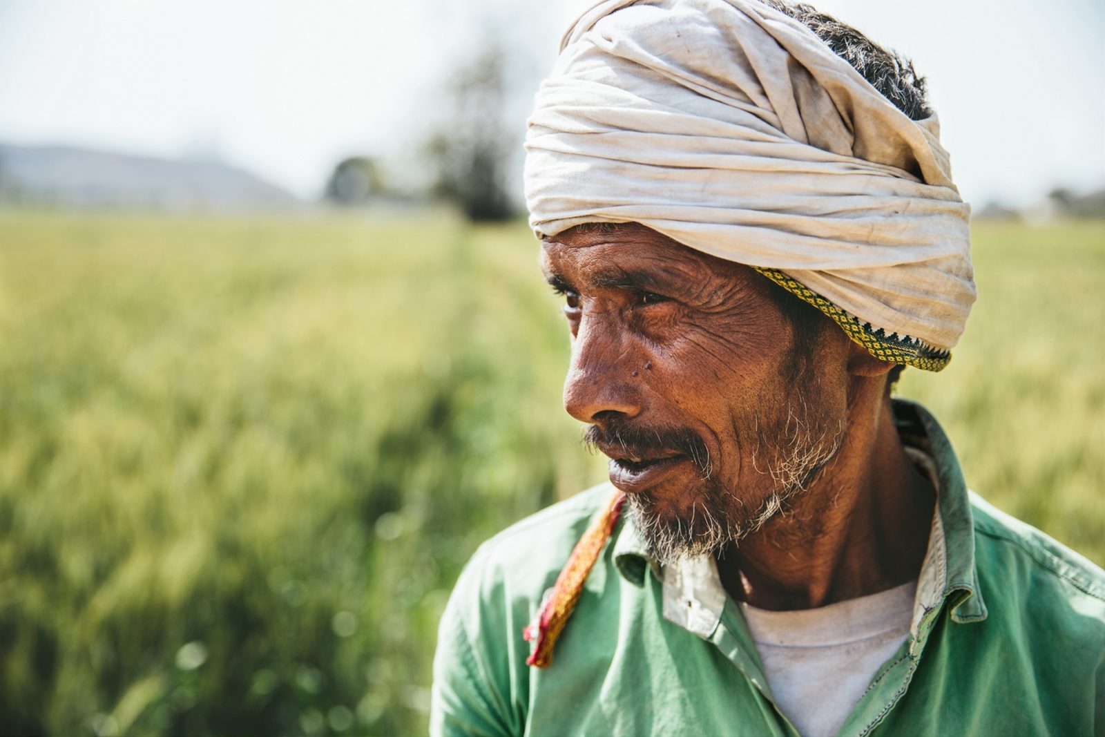 Photo of a farmer with a green field in the background