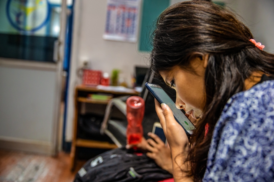 A woman with visual impairment closely examines her mobile phone