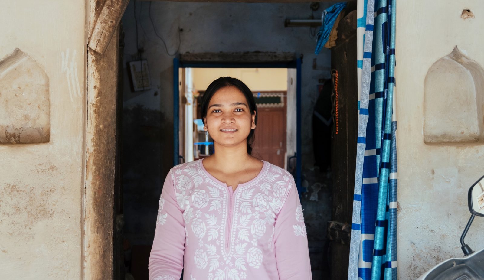 Photo of a girl smiling at the camera standing at a doorway