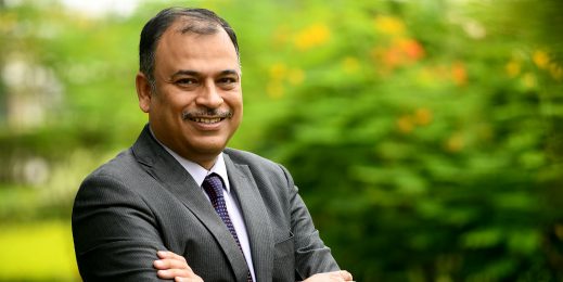 a man wearing a formal jacket and tie looking at the camera