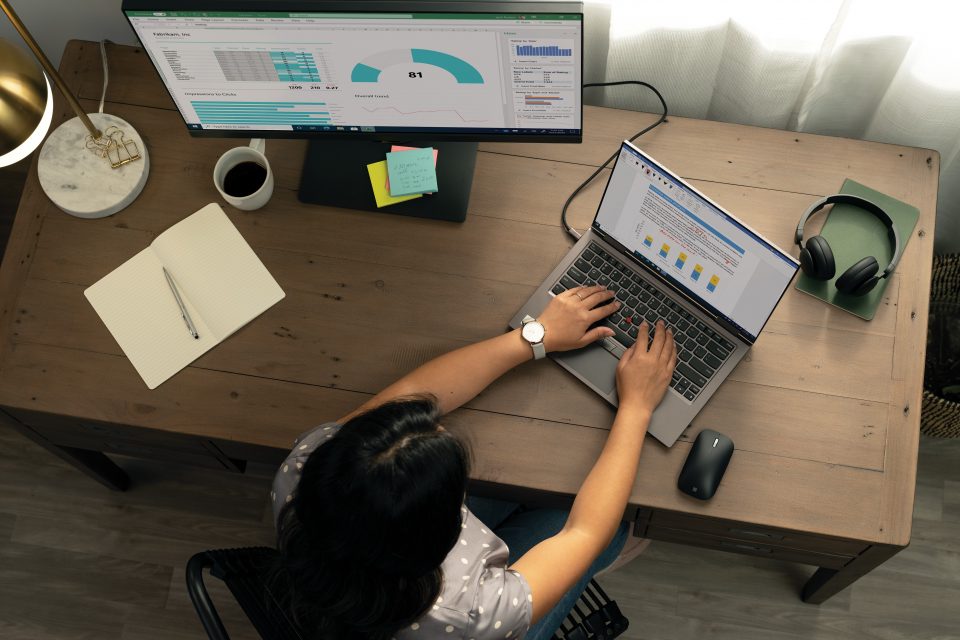 A high angle shot of a person working on their laptop with a desktop in the background