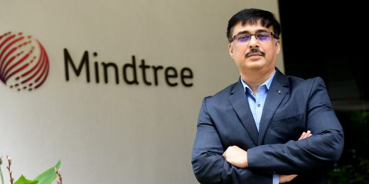 a man wearing a blue jacket with the mindtree logo in the background