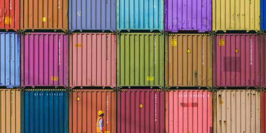 a man standing in front of a colorful stack of shipping containers