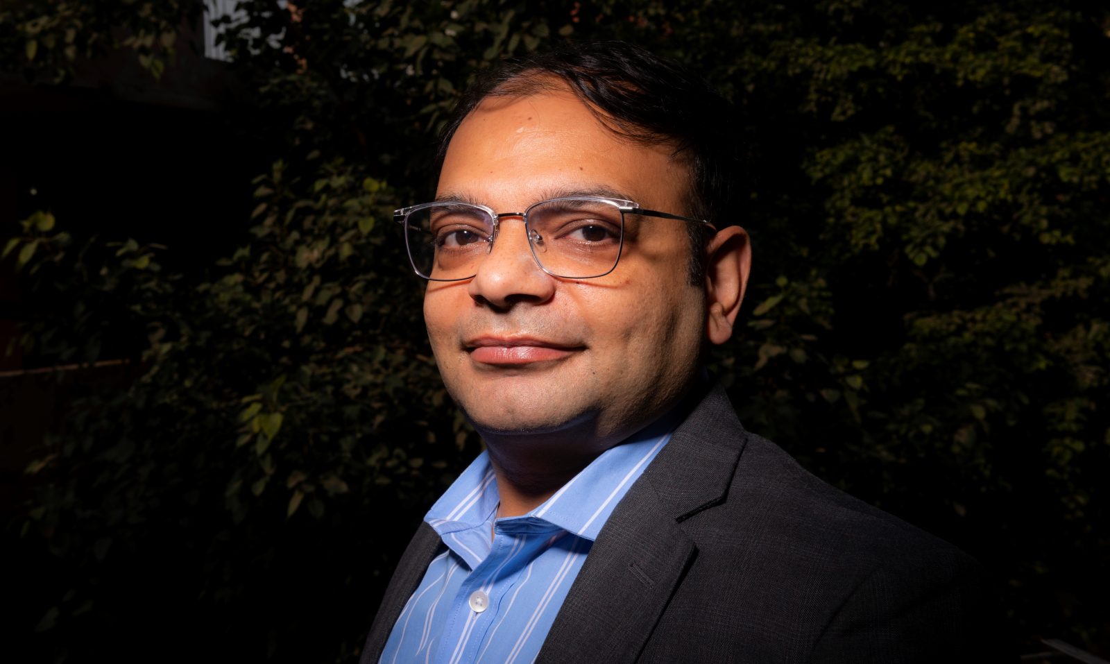 a man wearing glasses and a blue shirt looking at the camera