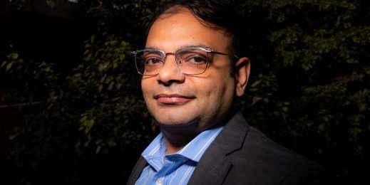 a man wearing glasses and a blue shirt looking at the camera