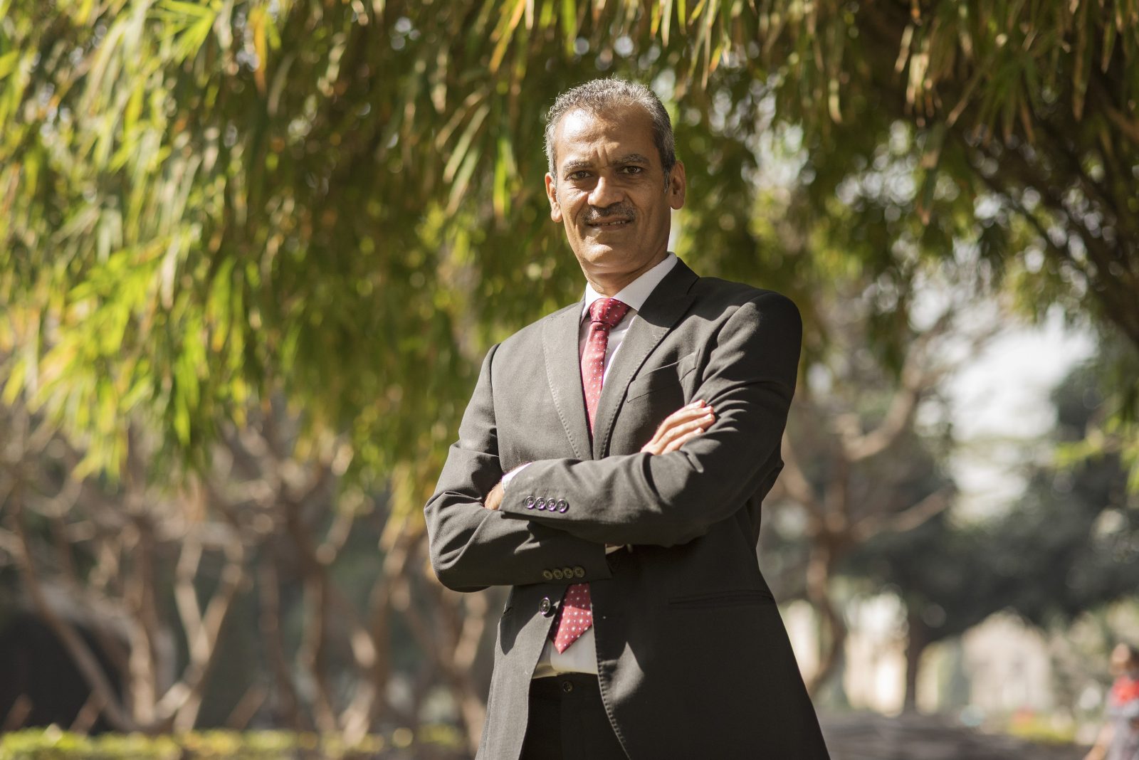 a man wearing a black suit looking at the camera with folded arms