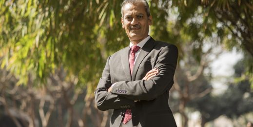 a man wearing a black suit looking at the camera with folded arms