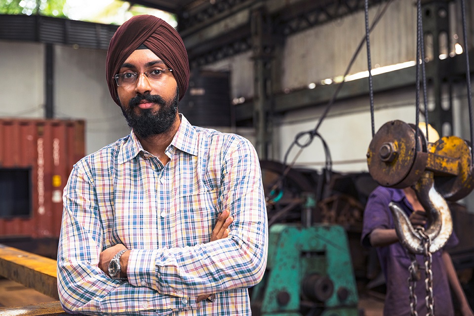 a man wearing a turban standing in front of manufacturing unit