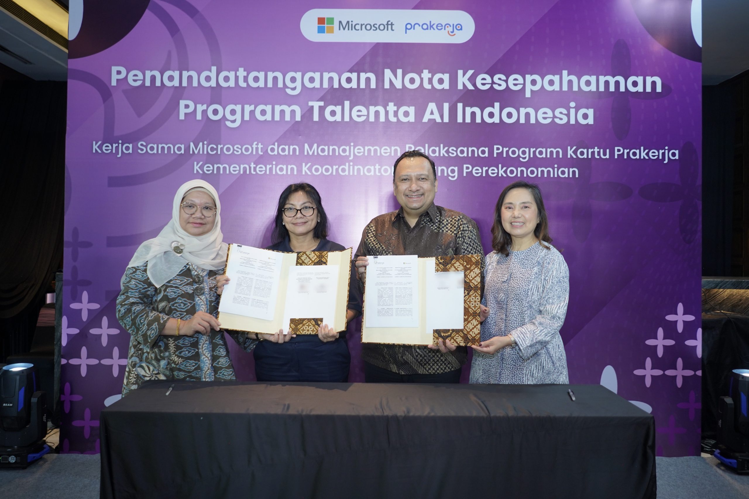 A photo of a man and three women holding a signed memorandum of understanding
