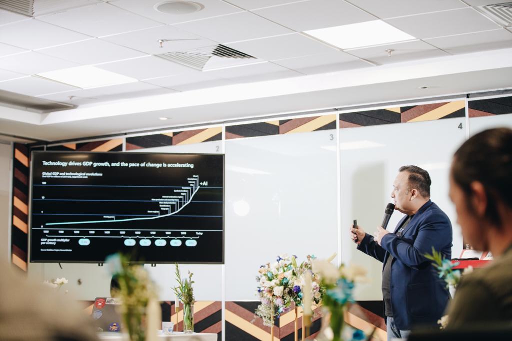 A man talking with a microphone pointing to the screen