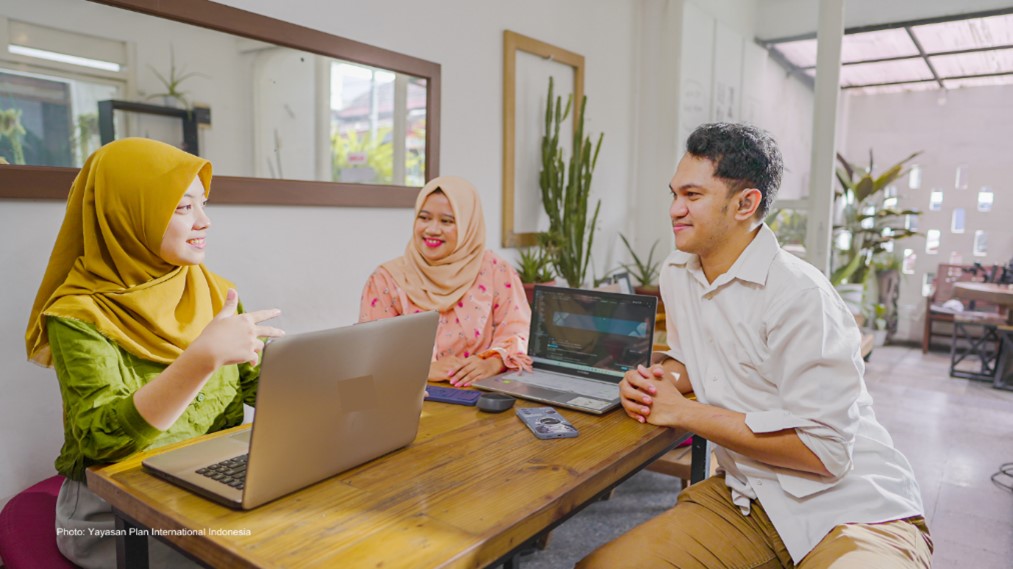 a group of people sitting at a table with laptops