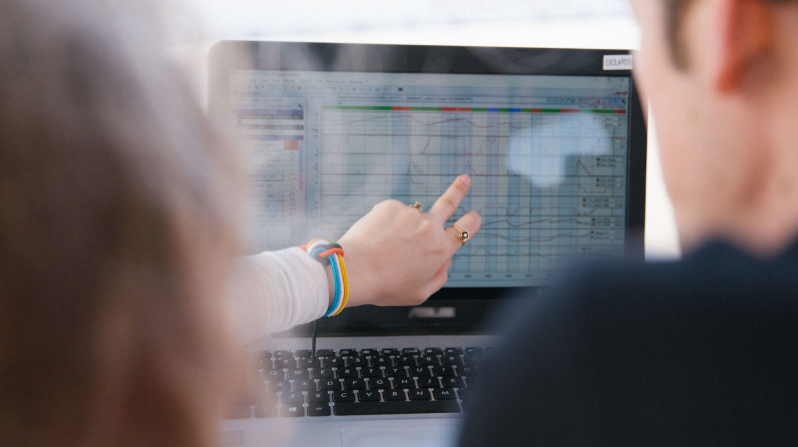 женская рука показывает что-т на графике, на экране ПК