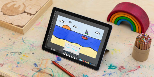 На детском столе карандаши, логические игрушки и планшет на базе Windows 10. На экране – рисунок в программе paint