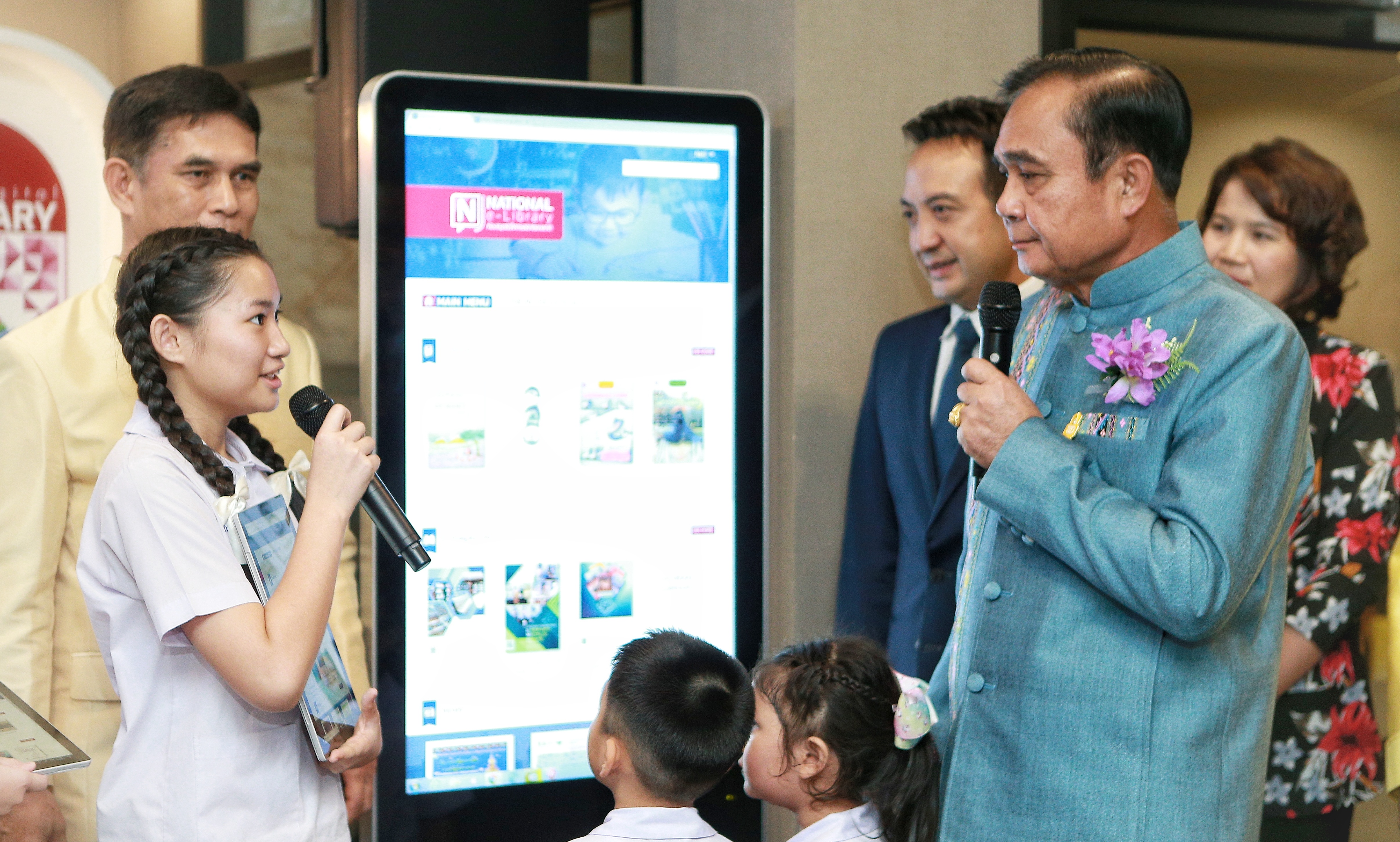 Thai Prime Minister in front of large screen talking to student