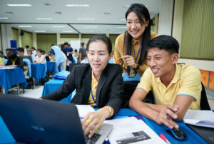 Two women and a man happily working on a laptop