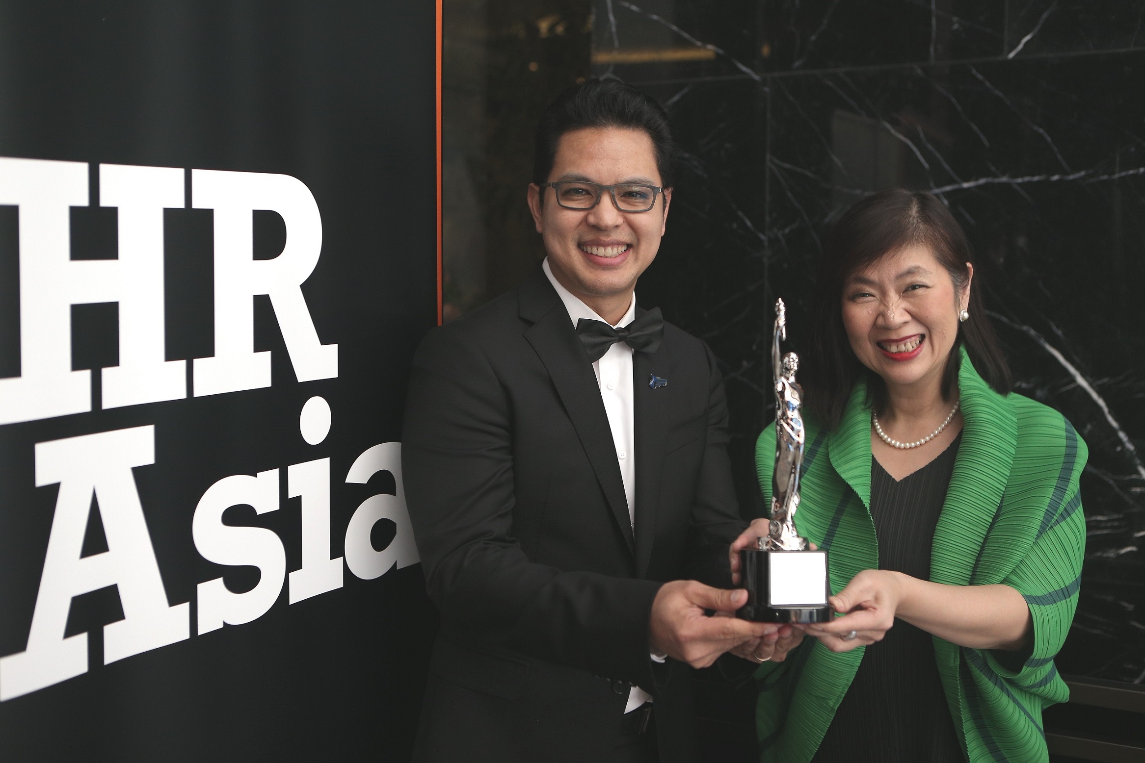 Man and woman in formal attire holding an award trophy