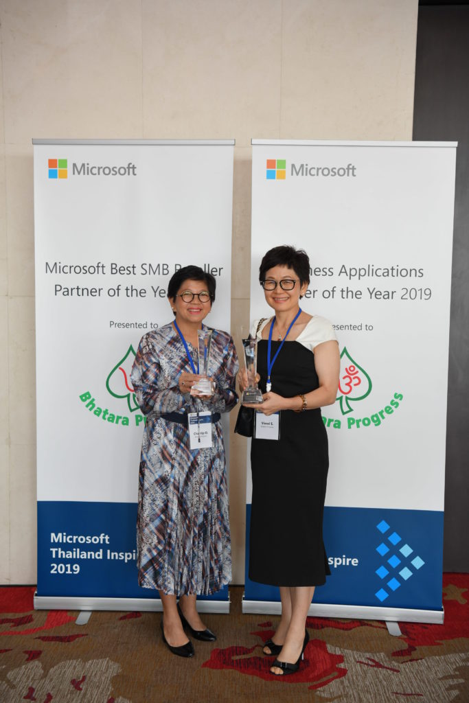 Executives and awards in front of signage
