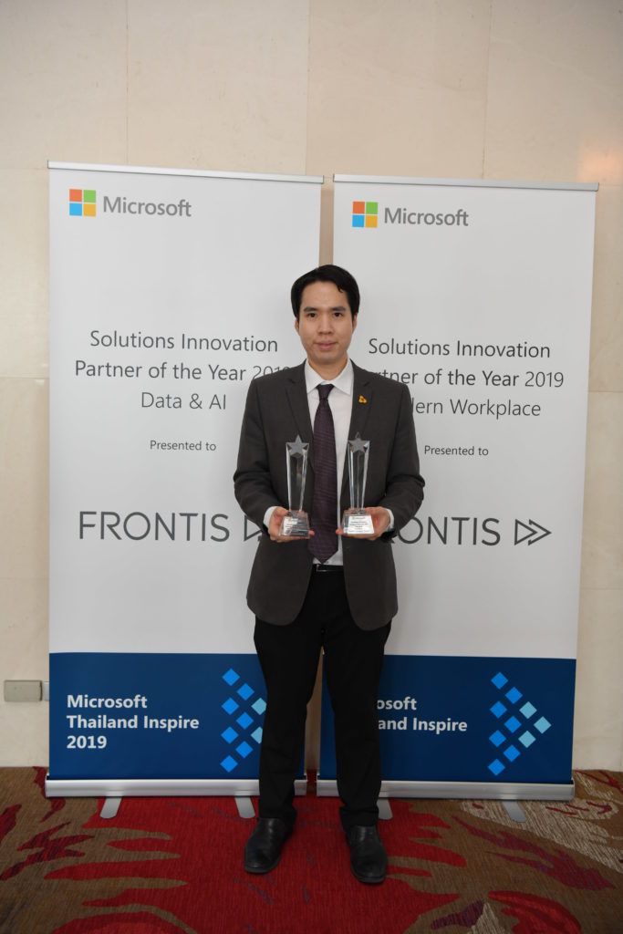 Executive and awards in front of signage