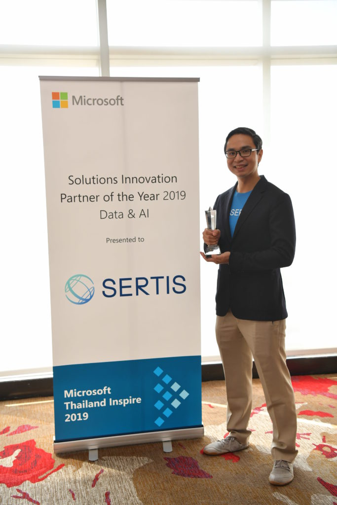 Executive and award in front of signage