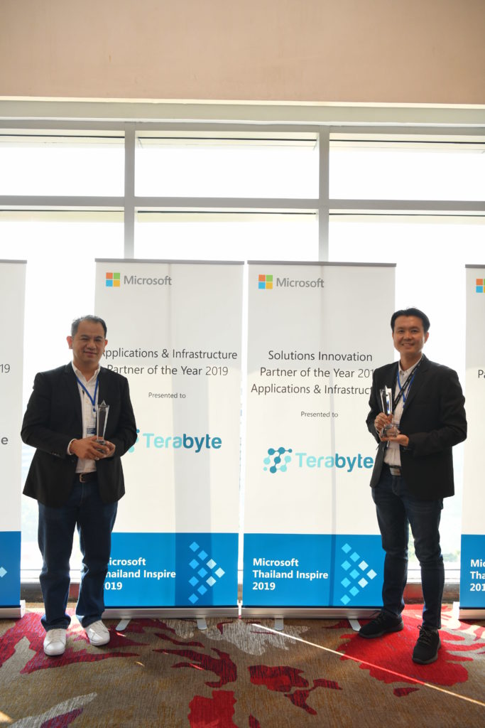 Executives and awards in front of signage